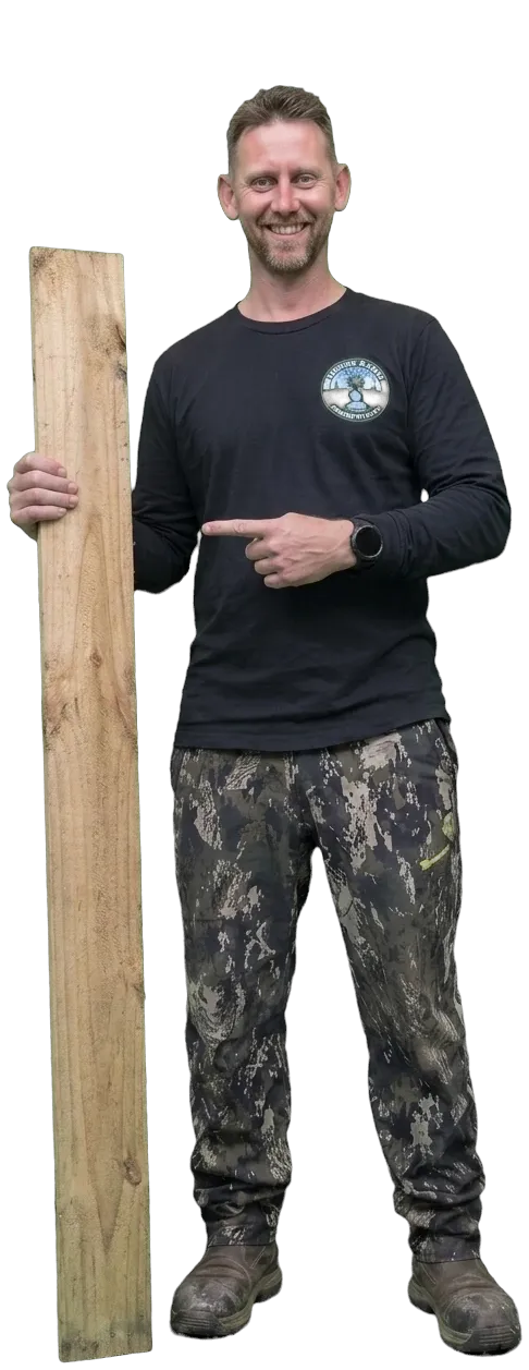 Mark Bannan, owner of Lawn In Order Nelson, smiling and holding a length of timber